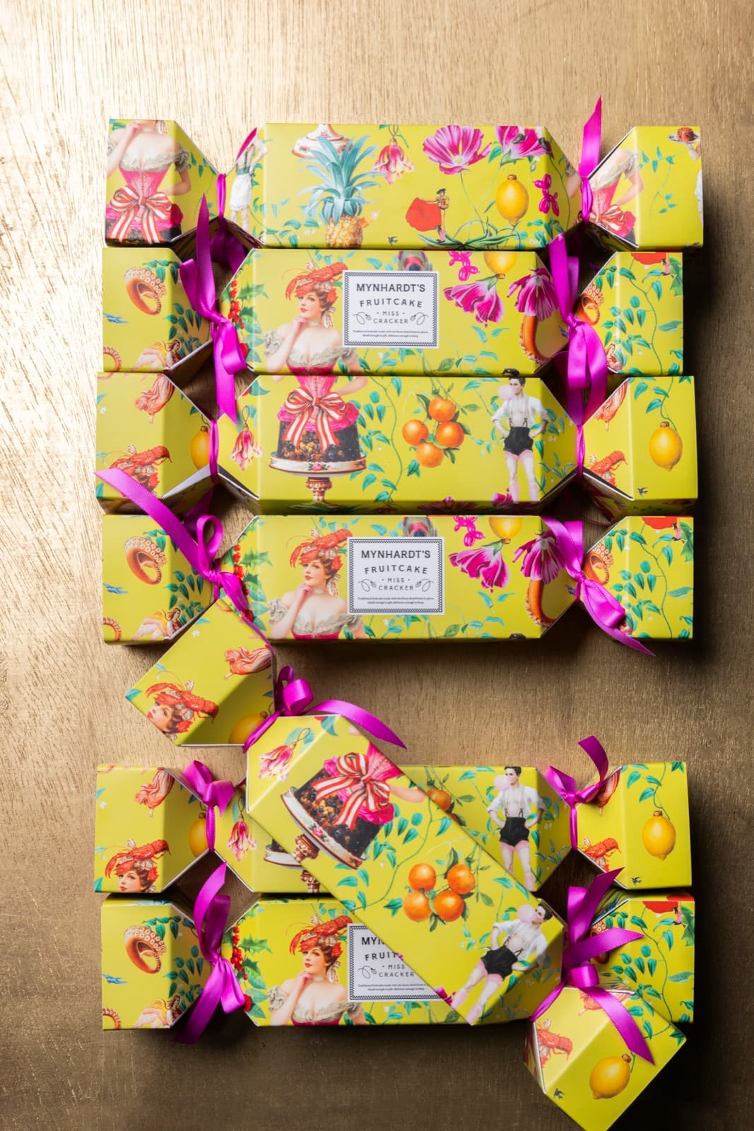 Miss Cracker fruitcakes in their chartreuse cracker wrapping, arranged on a brass surface