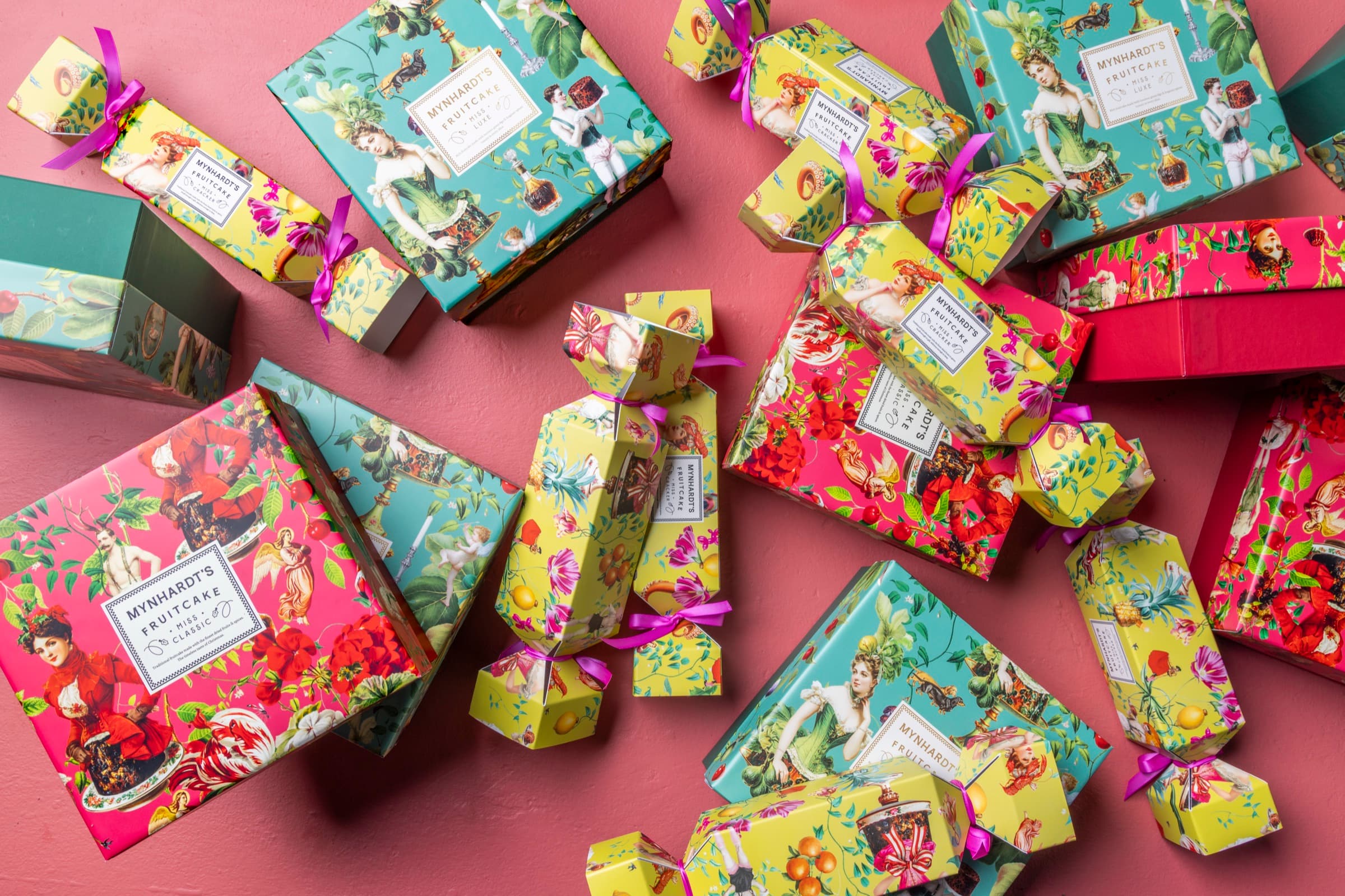 All three cakes in the collection, boxes and crackers in chartreuse, pink and green illustrated wrapping